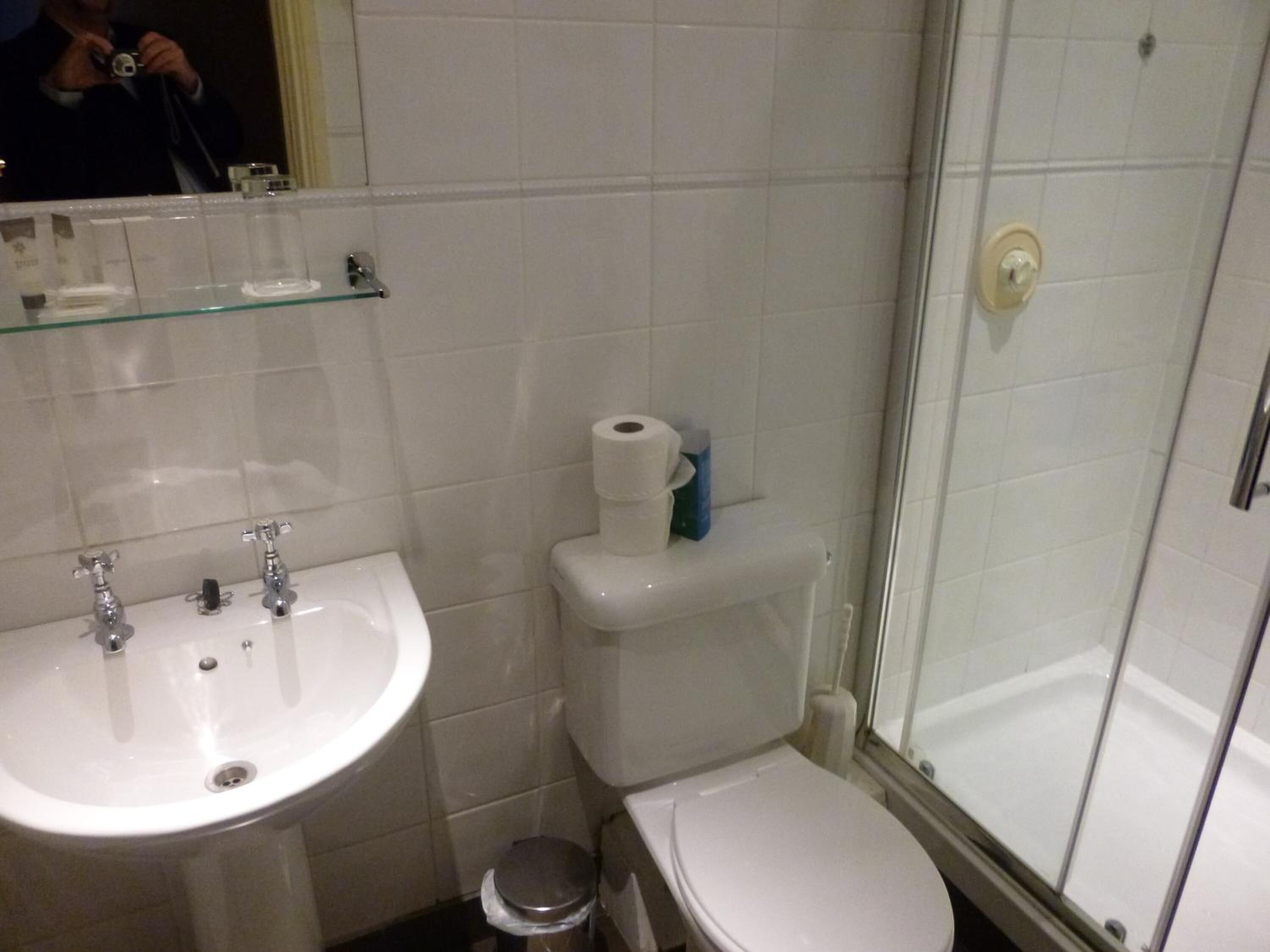A bathroom with a sink, toilet, and glass shower enclosure.