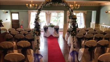A wedding aisle with white chairs, a red carpet, and floral decorations.