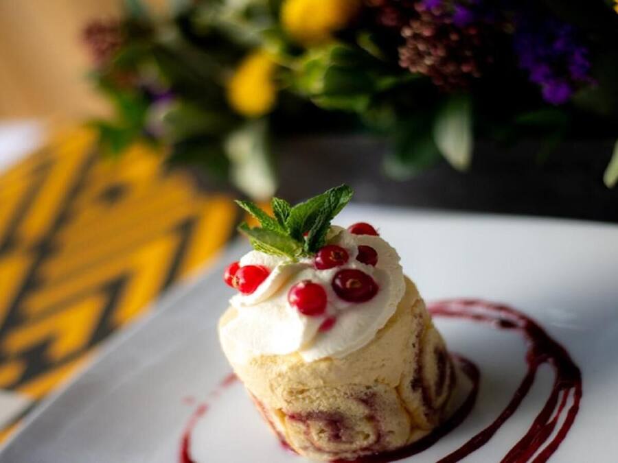 A dessert on a white plate with a red sauce pattern around it.
