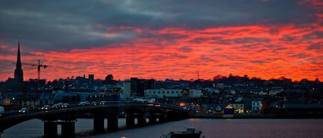 A sunset over a city with a bridge, boats, and buildings.