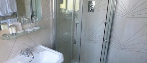 A modern bathroom with a glass-enclosed shower, a white sink, and a mirror above the sink.