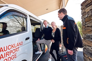A white van with "AUCKLAND AIRPORT MARRIOTT" written on it, parked outside a building with stone walls. - Auckland Airport Lodge (Auckland)