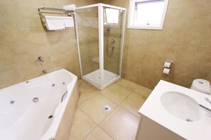 A bathroom with a glass-enclosed shower, a bathtub, and a sink.