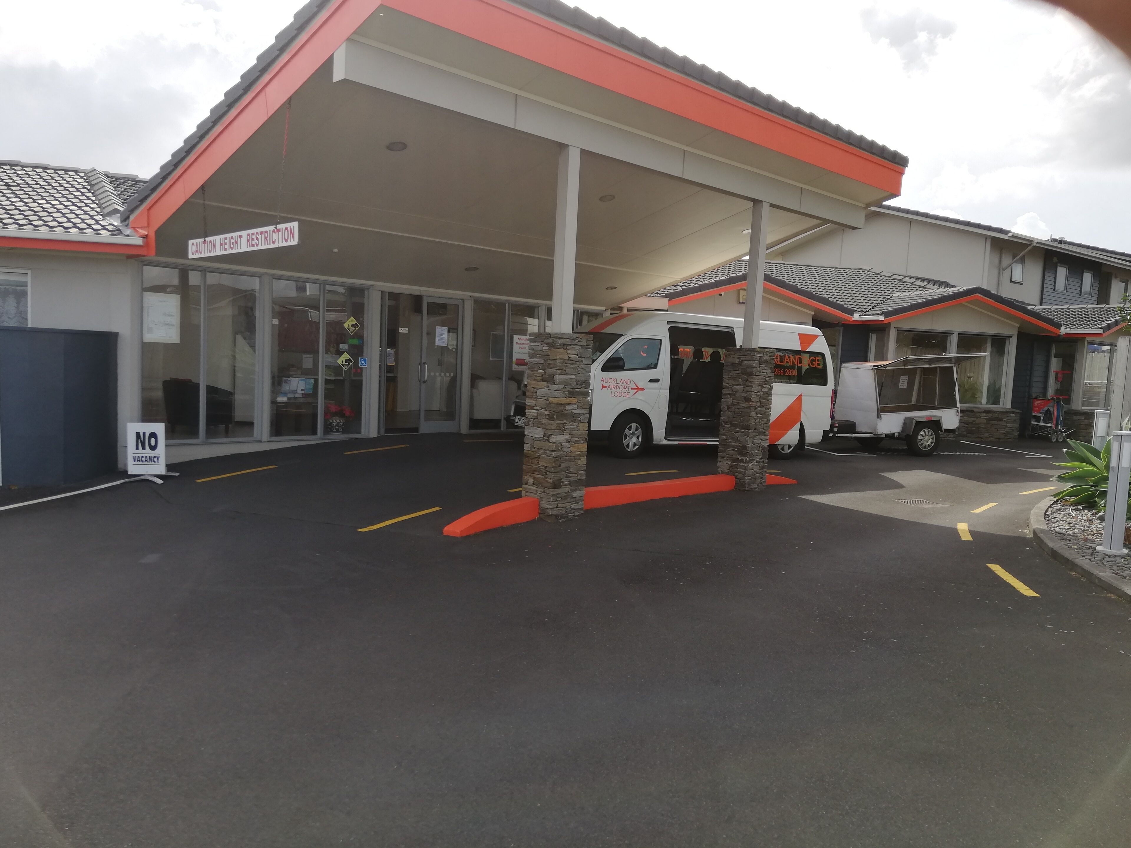A building with a covered entrance, a van parked in front, and a 'No Vacancy' sign.