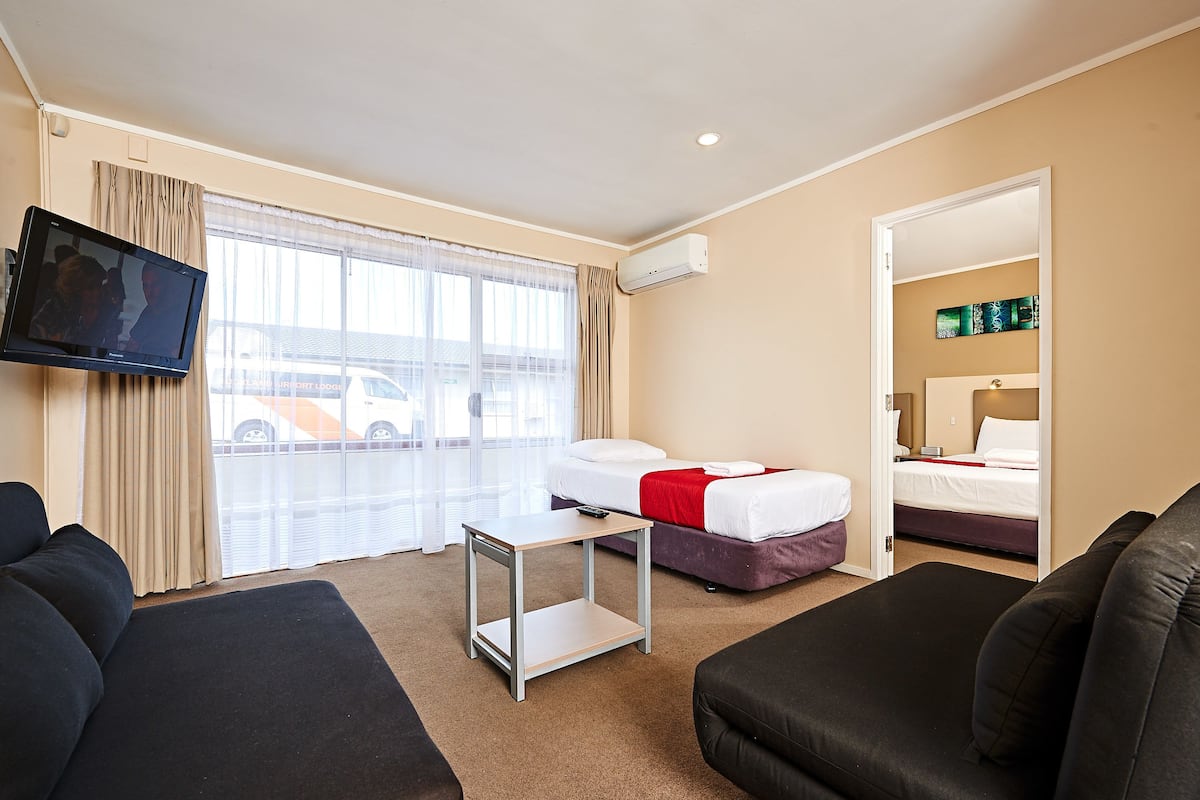 Una habitación de hotel con una cama, televisor, una mesita y un sofá.