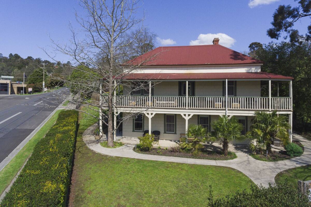 A two-story house with a red roof, a balcony, and a well-maintained lawn.