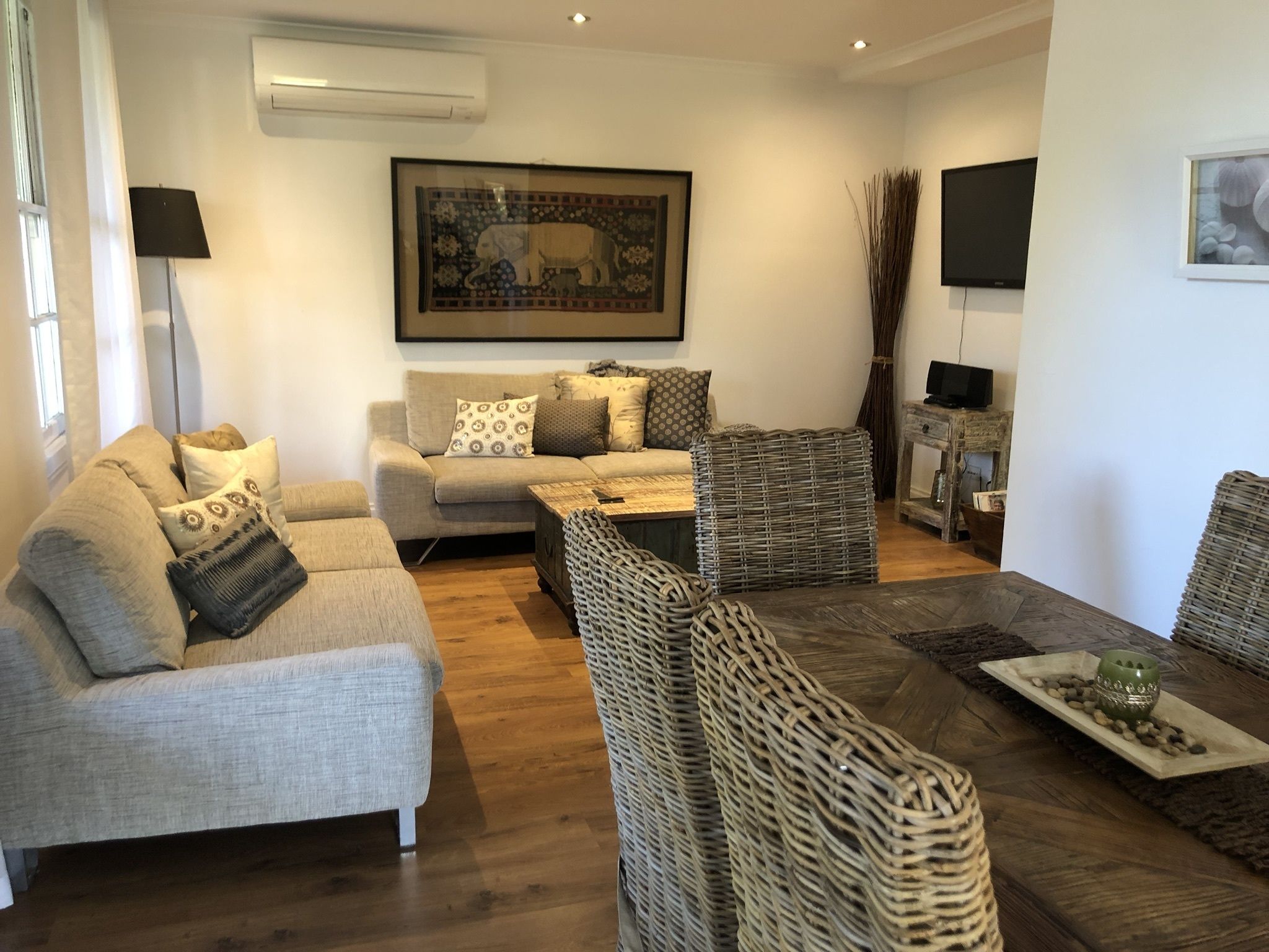 A living room with a sofa, two armchairs, a coffee table, and a TV.