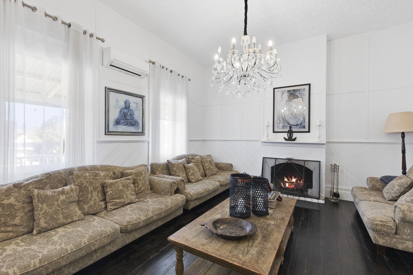 Una sala de estar con un sofá, una mesa de centro de madera, una chimenea y un candelabro.