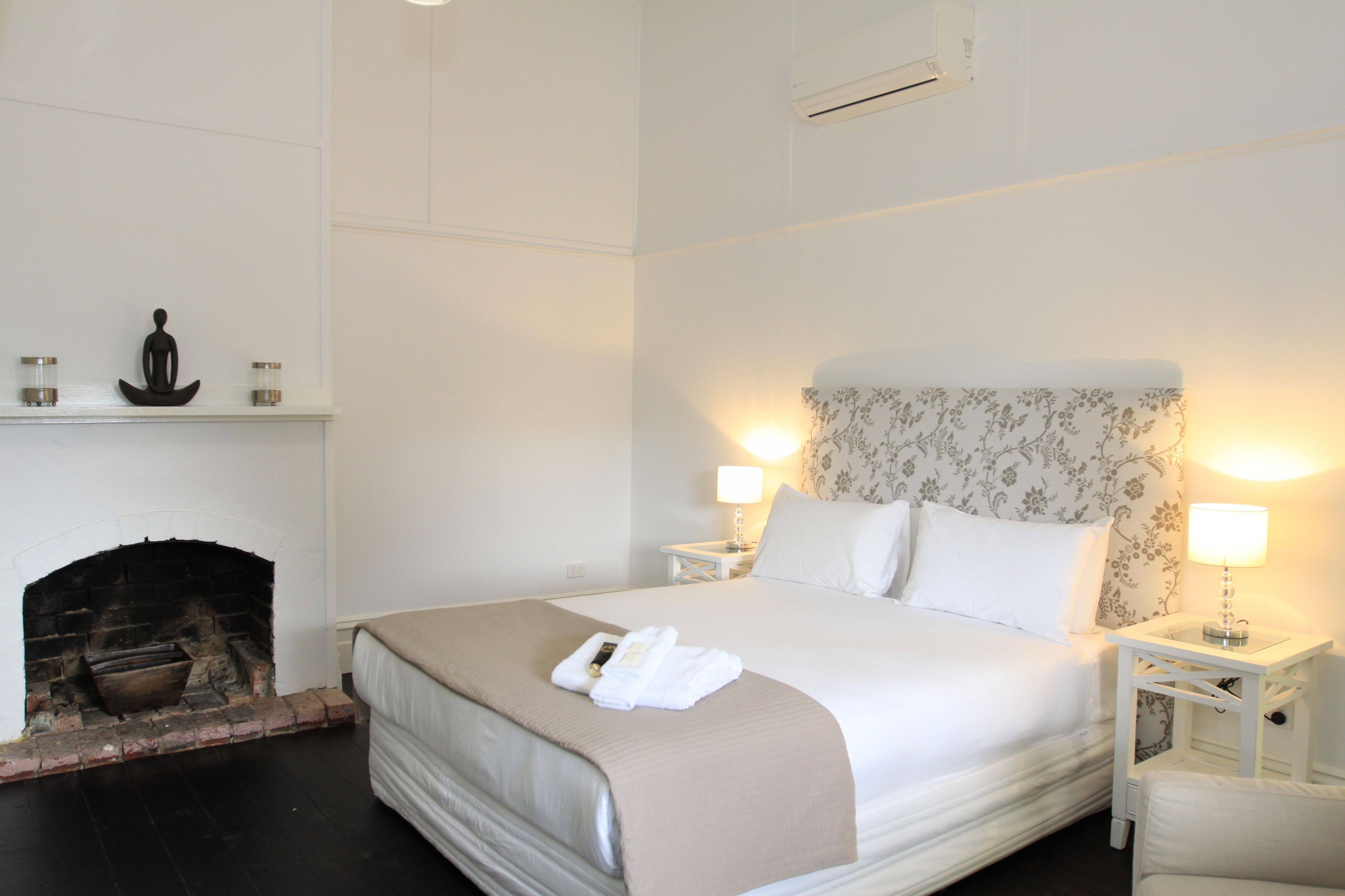Une chambre d’hôtel avec un grand lit, une cheminée et deux lampes de chevet.