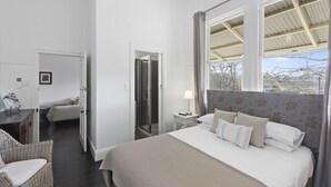 Een slaapkamer met een groot bed, een nachtkastje met een lamp, een stoel, een kledingkast en een douchegedeelte.