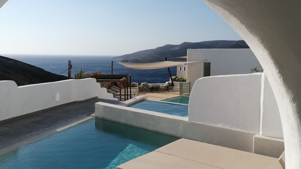 A clear blue pool with white walls and a view of the sea. There are lounge chairs and a small table. - Pylaia Boutique Hotel & Spa (Astypalaia)