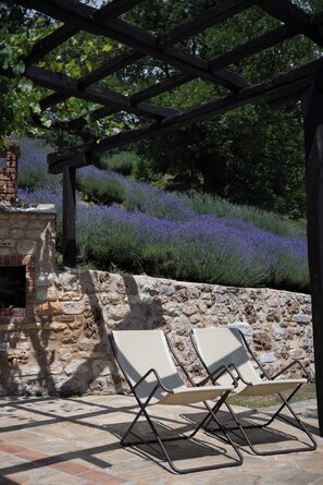 A stone fireplace, two lounge chairs, and a pergola with a view of lavender fields. - Ktima Bellou (Katerini)