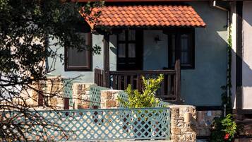 Una casa con techo de tejas rojas, paredes de piedra y un pequeño balcón con celosía.