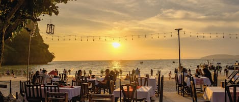 Un restaurante frente al mar con mesas y sillas dispuestas para comer, con vistas al océano.