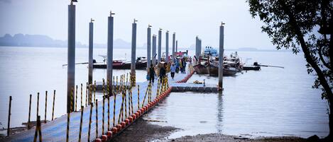 A dock with boats, a pier with bollards, and a water body with distant landforms.