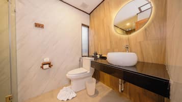Een moderne badkamer met een marmeren wand, een houten wastafelmeubel, een witte wasbak en een toilet.