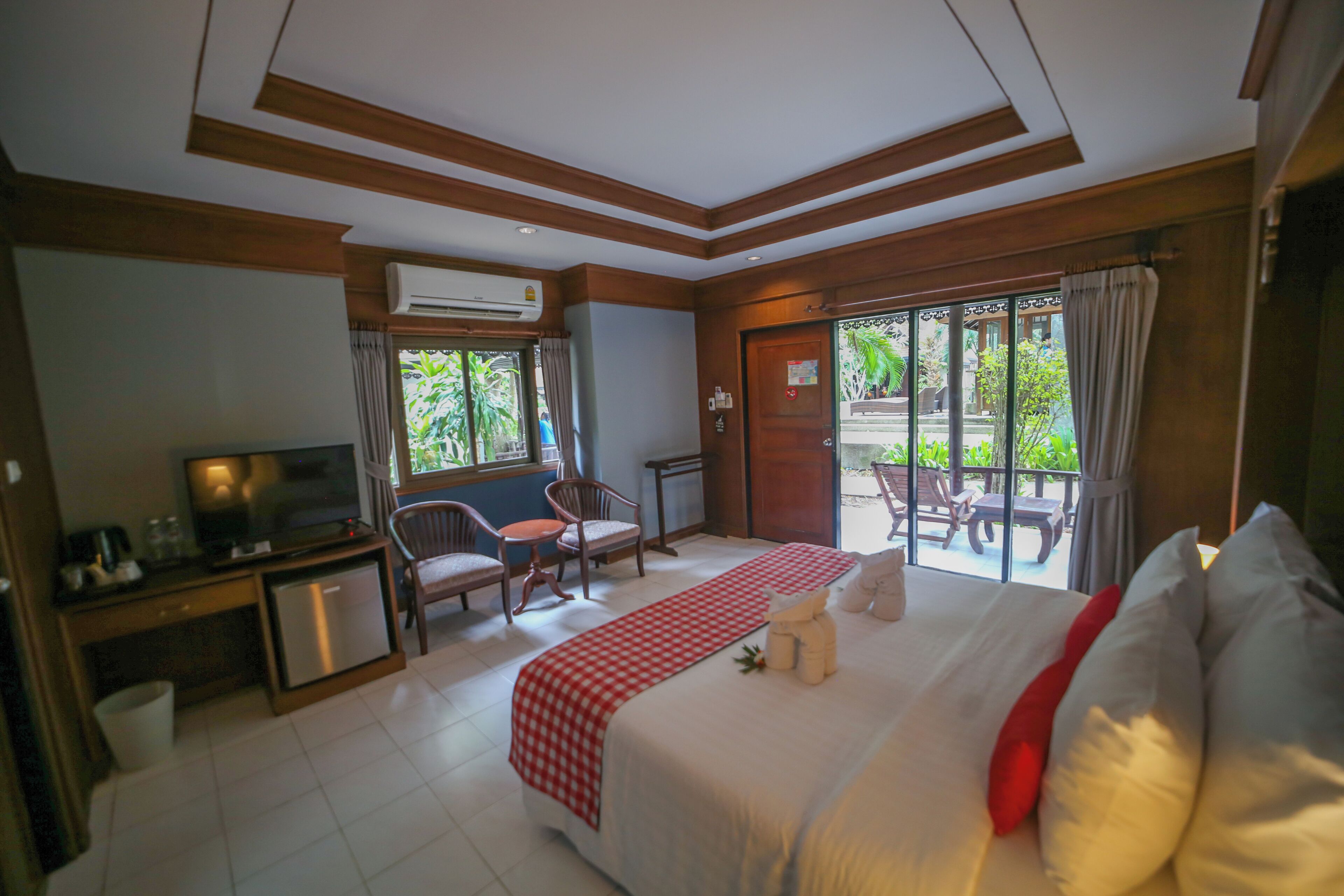 A hotel room with a bed, a desk with a television, a chair, and a view of the outdoors.
