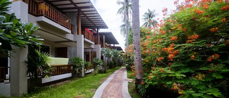 A pathway leading to a modern building with balconies and lush greenery.