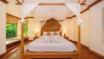 A four-poster canopy bed with a wooden frame, white bedding, and a "WELCOME BACK" sign.