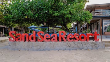 A sign for SandSeaResort with a stone base and red lettering.