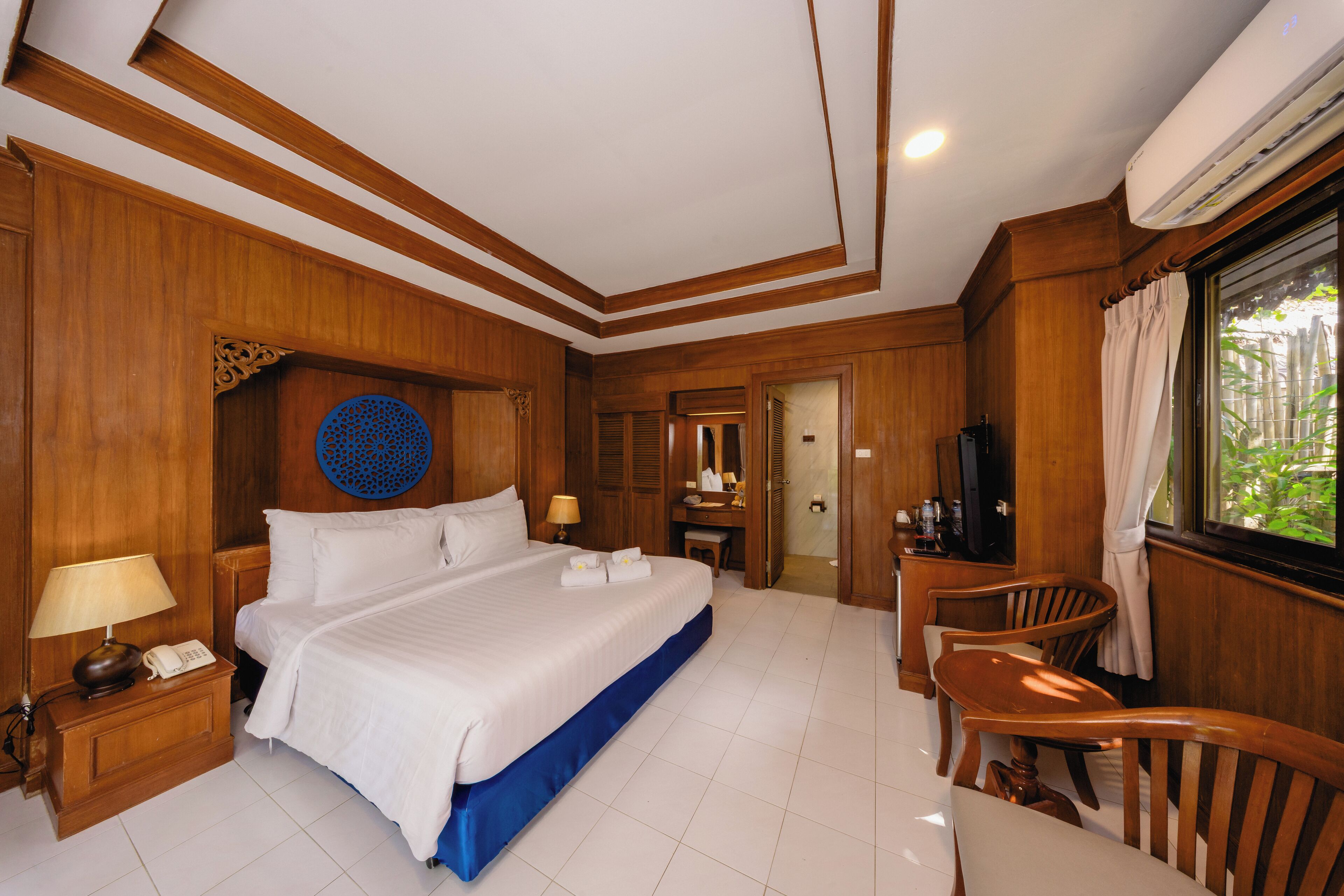 Une chambre d’hôtel avec un grand lit, un bureau avec une chaise, une télévision et une fenêtre avec des rideaux.