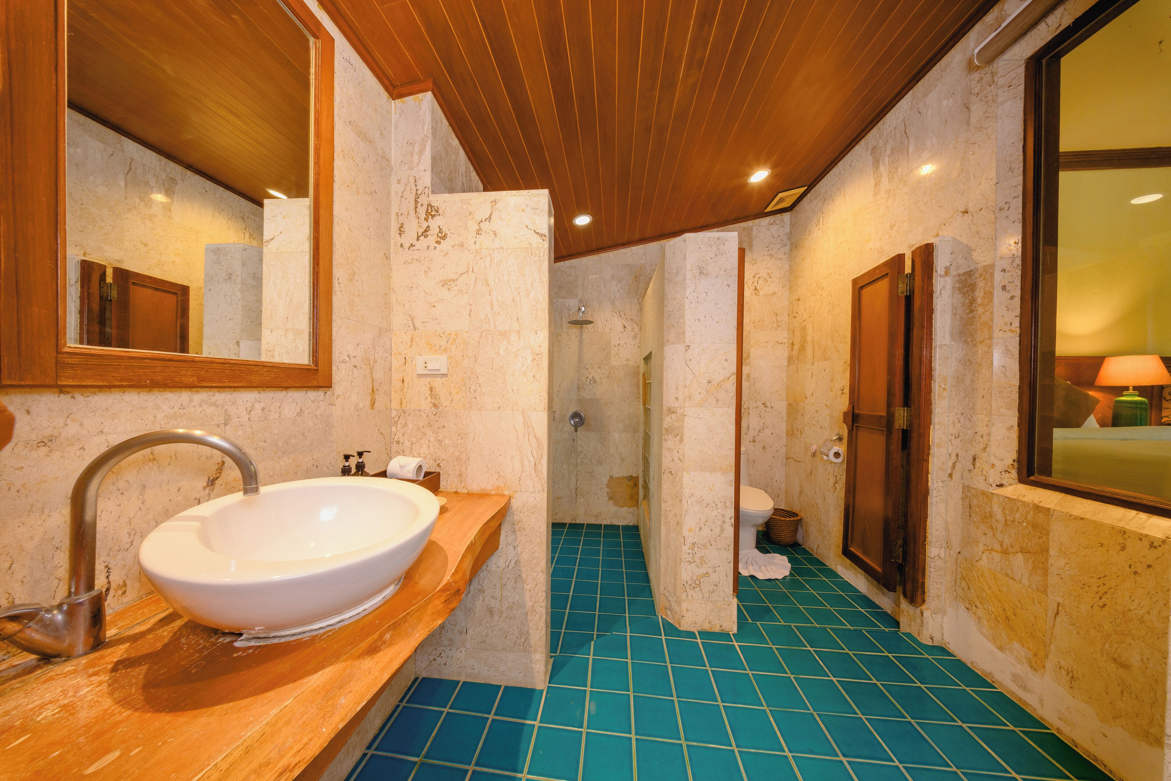 Une salle de bain avec un lavabo blanc, un meuble-lavabo en bois et un sol carrelé de carreaux bleus.