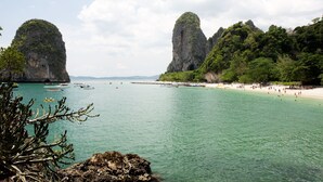 A coastal area with clear turquoise water, rocky cliffs, and a sandy beach. - Sand Sea Resort (Krabi)