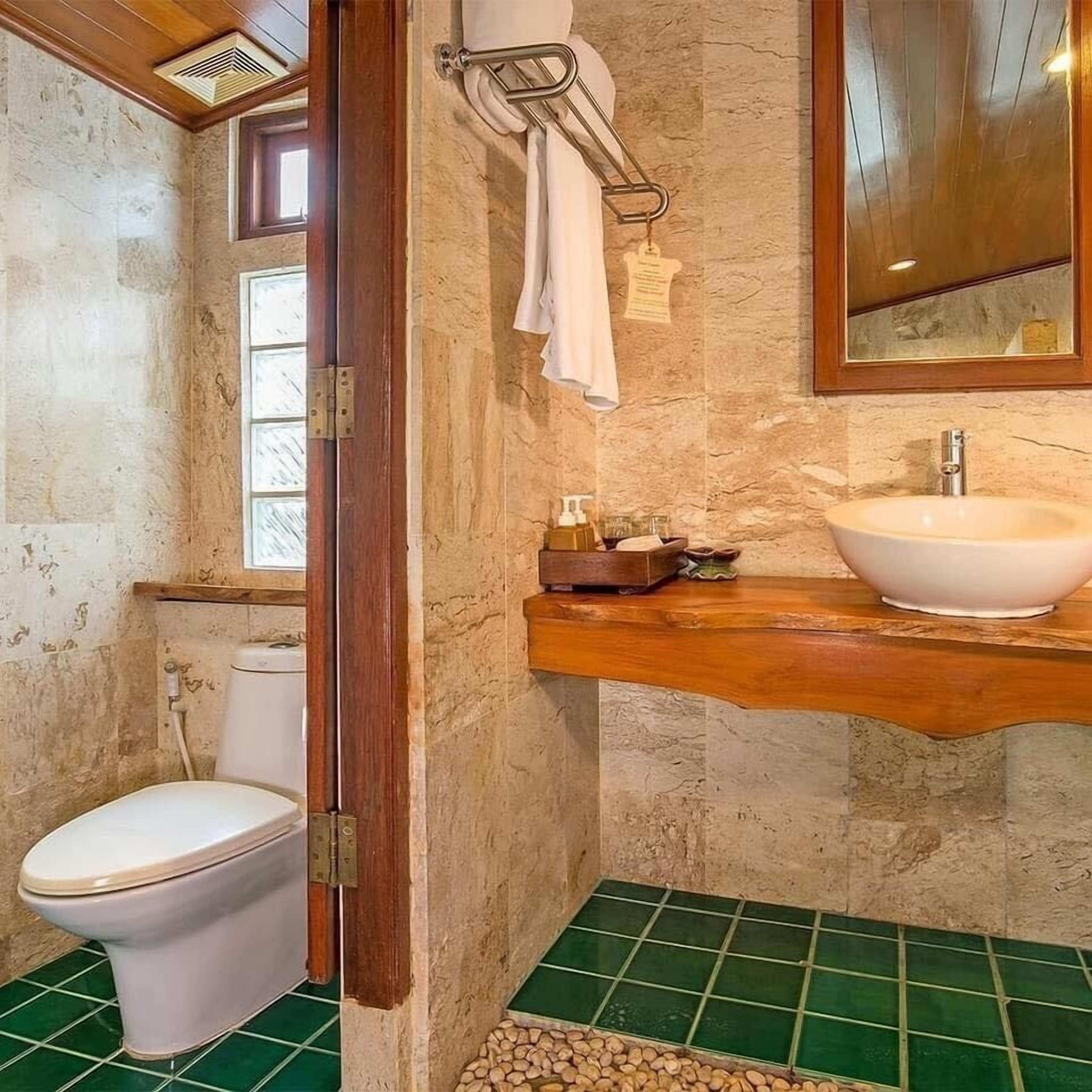 A bathroom with a toilet, a sink, and a mirror.
