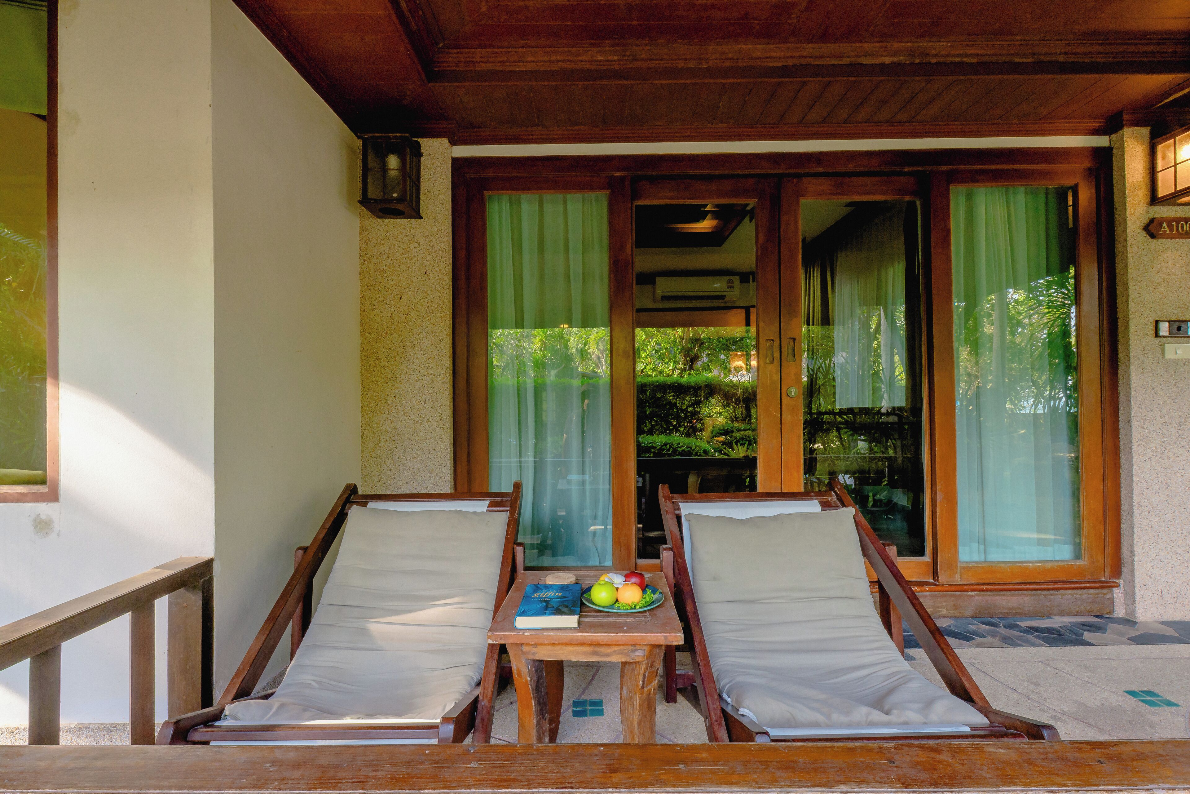 A wooden deck with two lounge chairs and a table with a book and fruit.