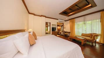 A hotel room with a large bed, a wooden headboard, a television, a sofa, and a desk.