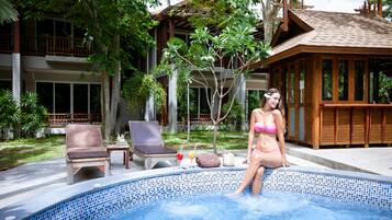 Relax by the serene pool surrounded by lush greenery and lounge in style with comfortable seating and amenities.