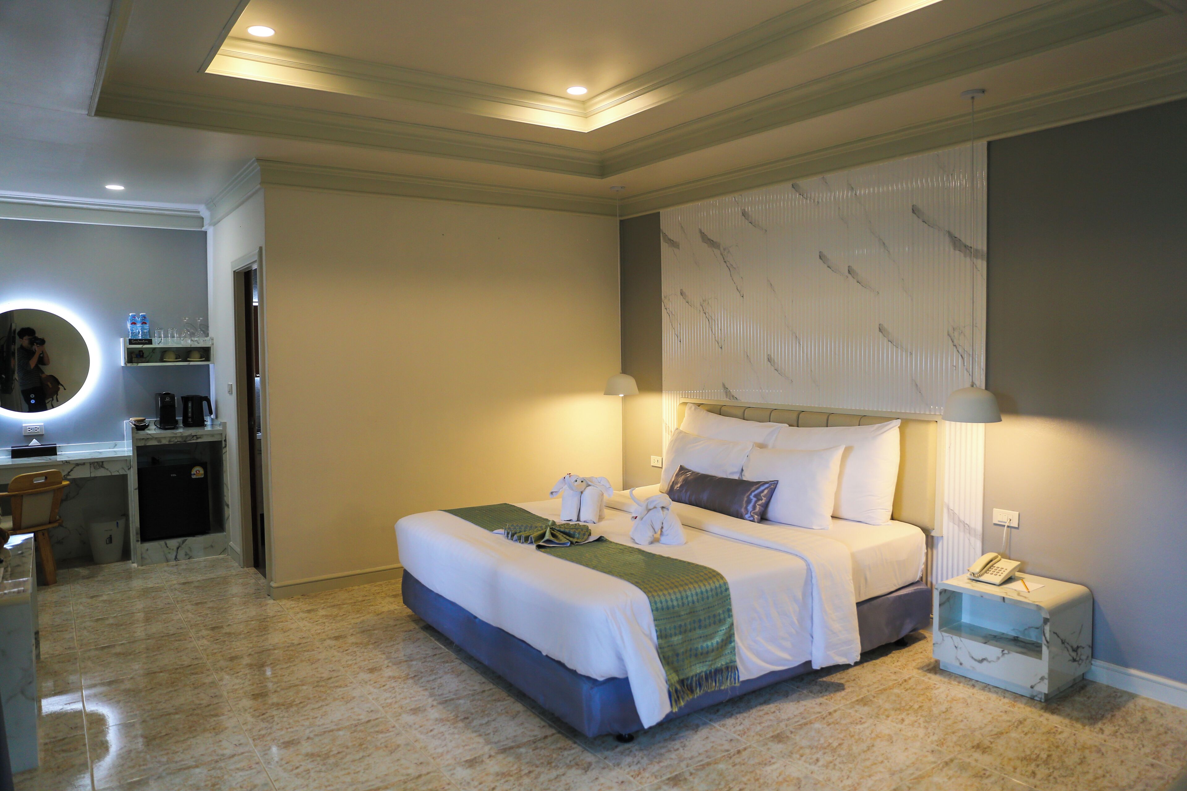 Una habitación de hotel con una cama grande, un escritorio con cafetera y un espejo.