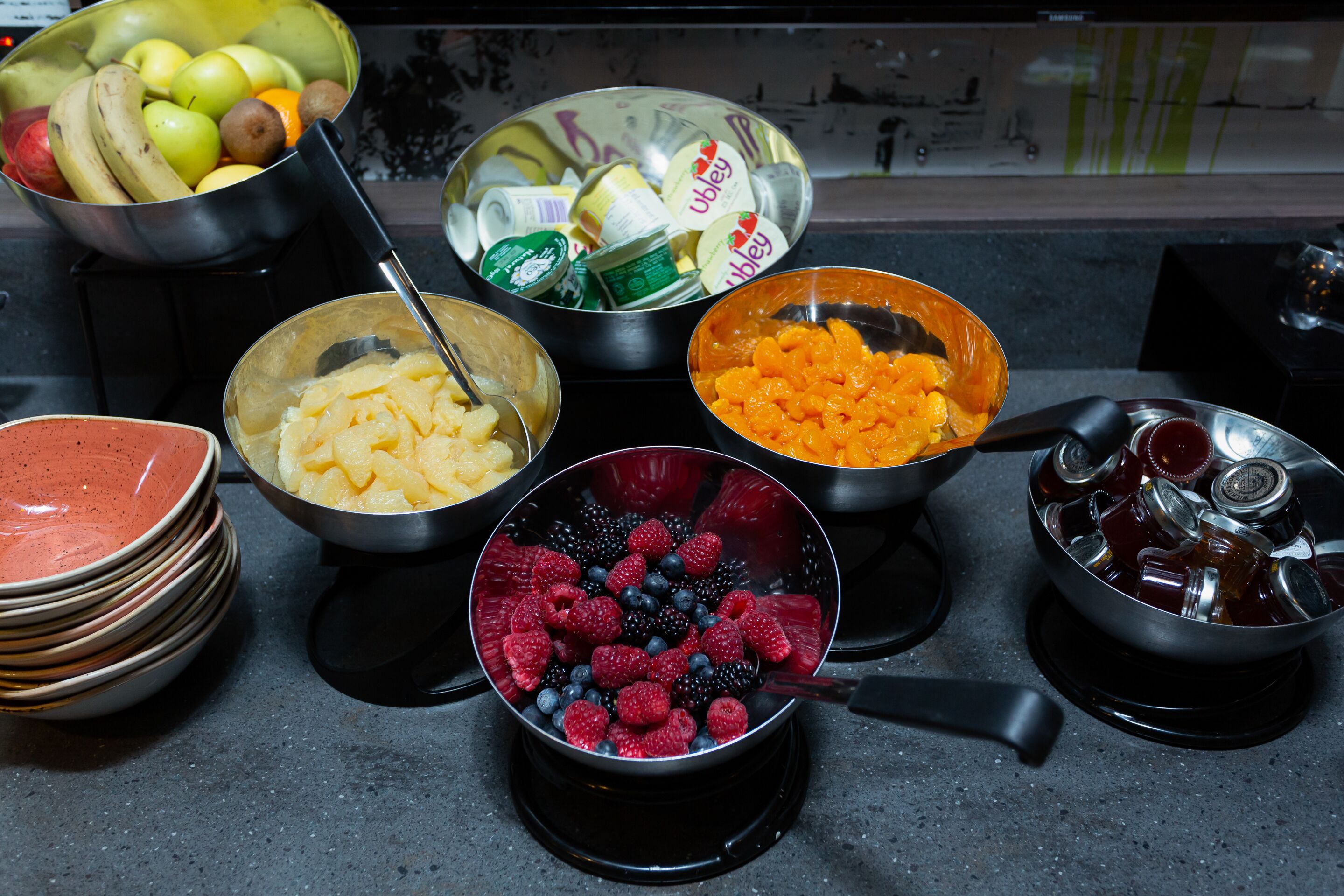 A kitchen counter with various bowls containing fruits and vegetables.