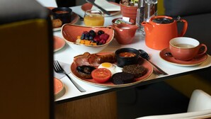 Una mesa de desayuno con diversos platos, un periódico y una silla amarilla.
