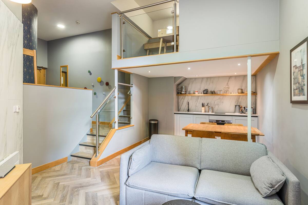 Un intérieur moderne comprenant un canapé, un escalier, une cuisine et un coin repas.