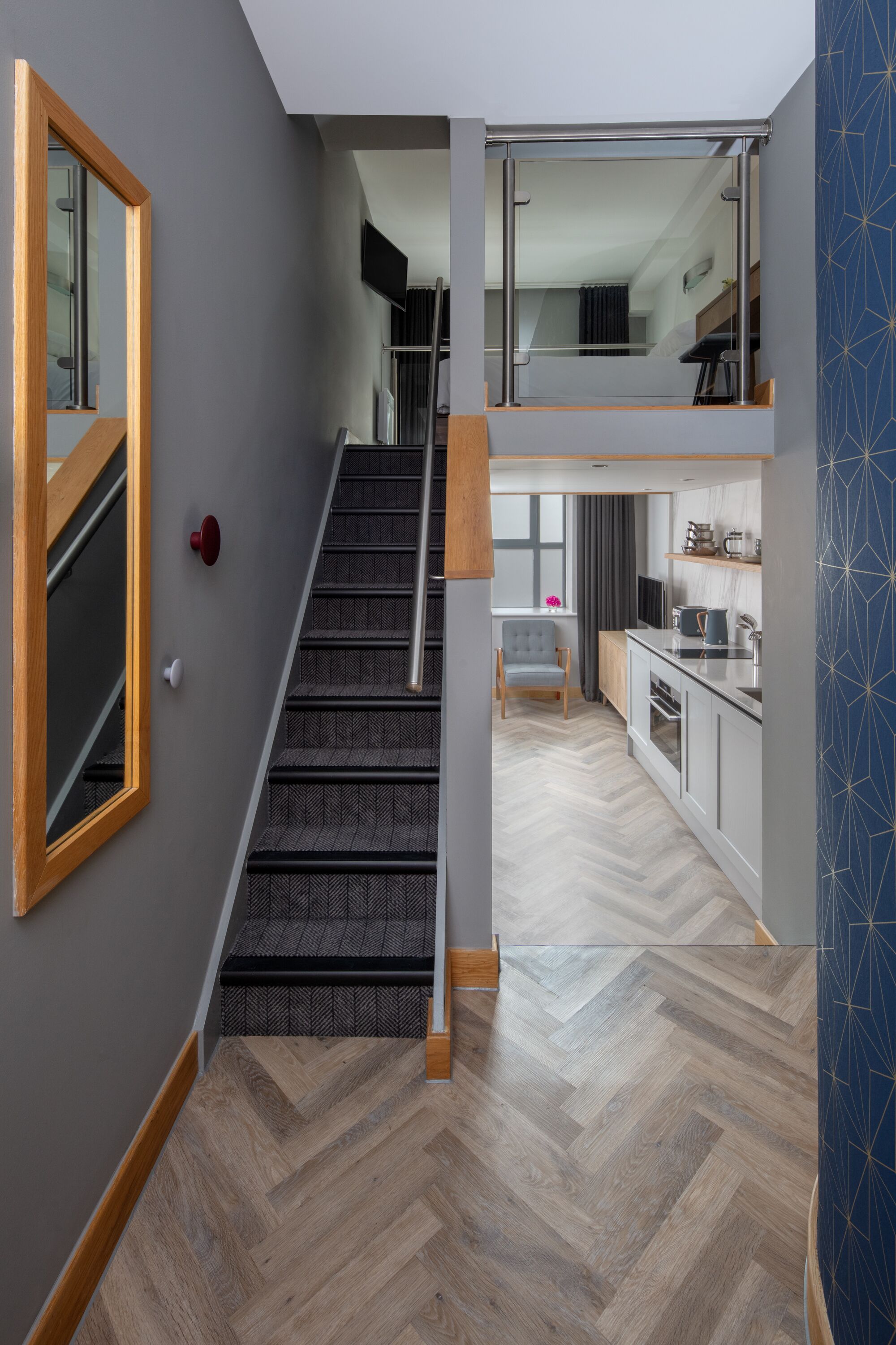 A modern interior with a staircase leading to a second floor, a kitchen area, and a seating area with a chair and a table.