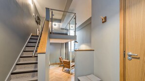 Un interior moderno con una escalera, un muro espejado y una puerta de madera.