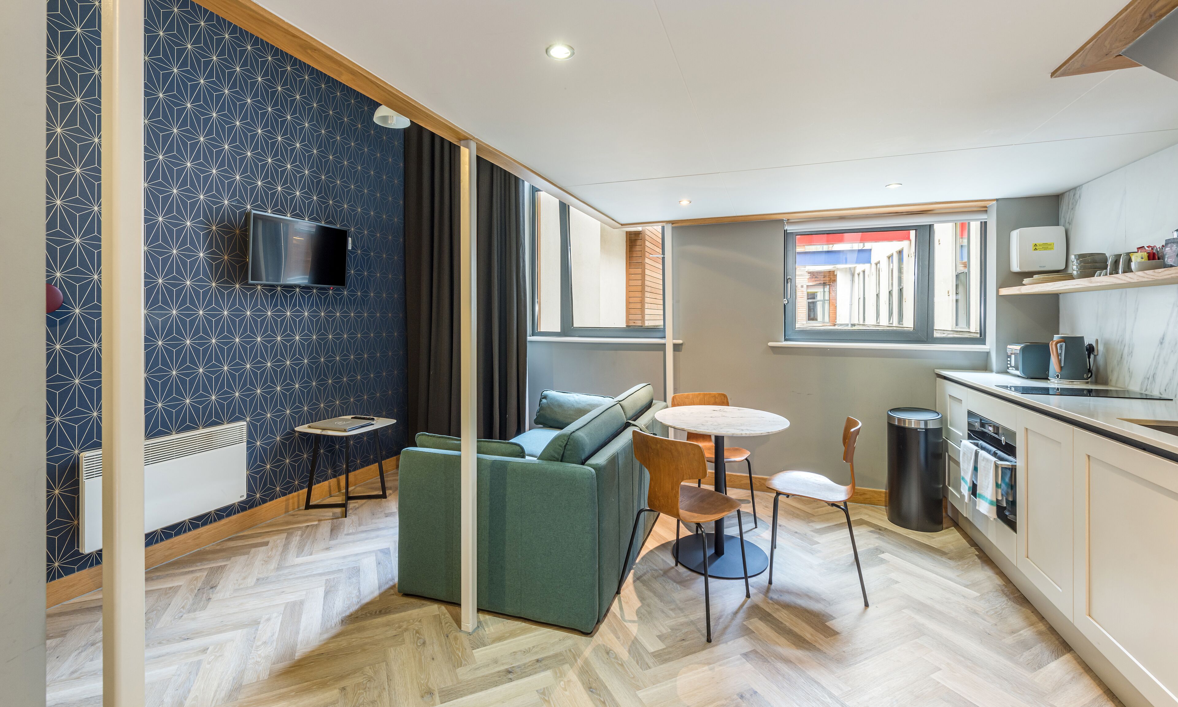 A modern interior with a sofa, a small table, a TV, and a kitchen area.