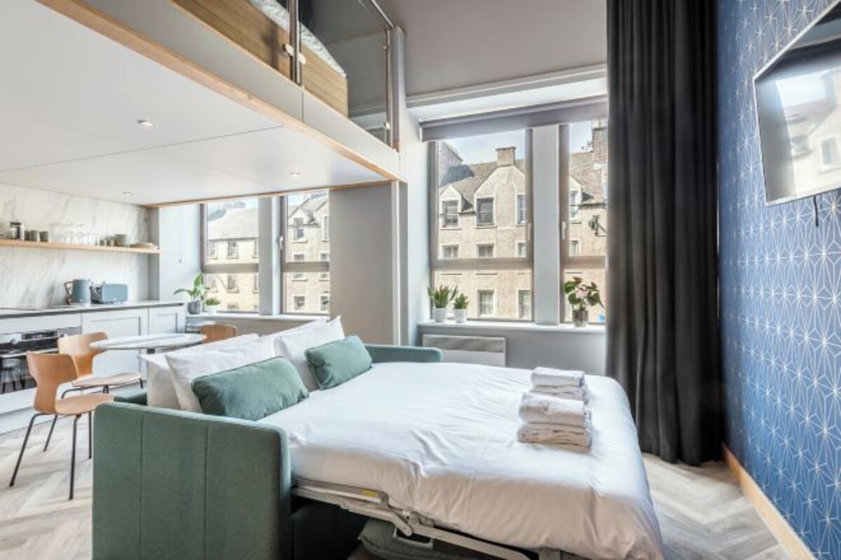 Ett modernt hotellrum med en säng, ett skrivbord och utsikt över staden.