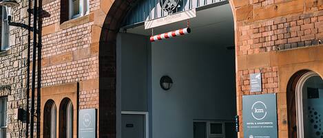 En murstensbygning med en stor buet indgang, et skilt med teksten "MAX HEADROOM" og et skilt for "HOTEL & APARTMENTS".