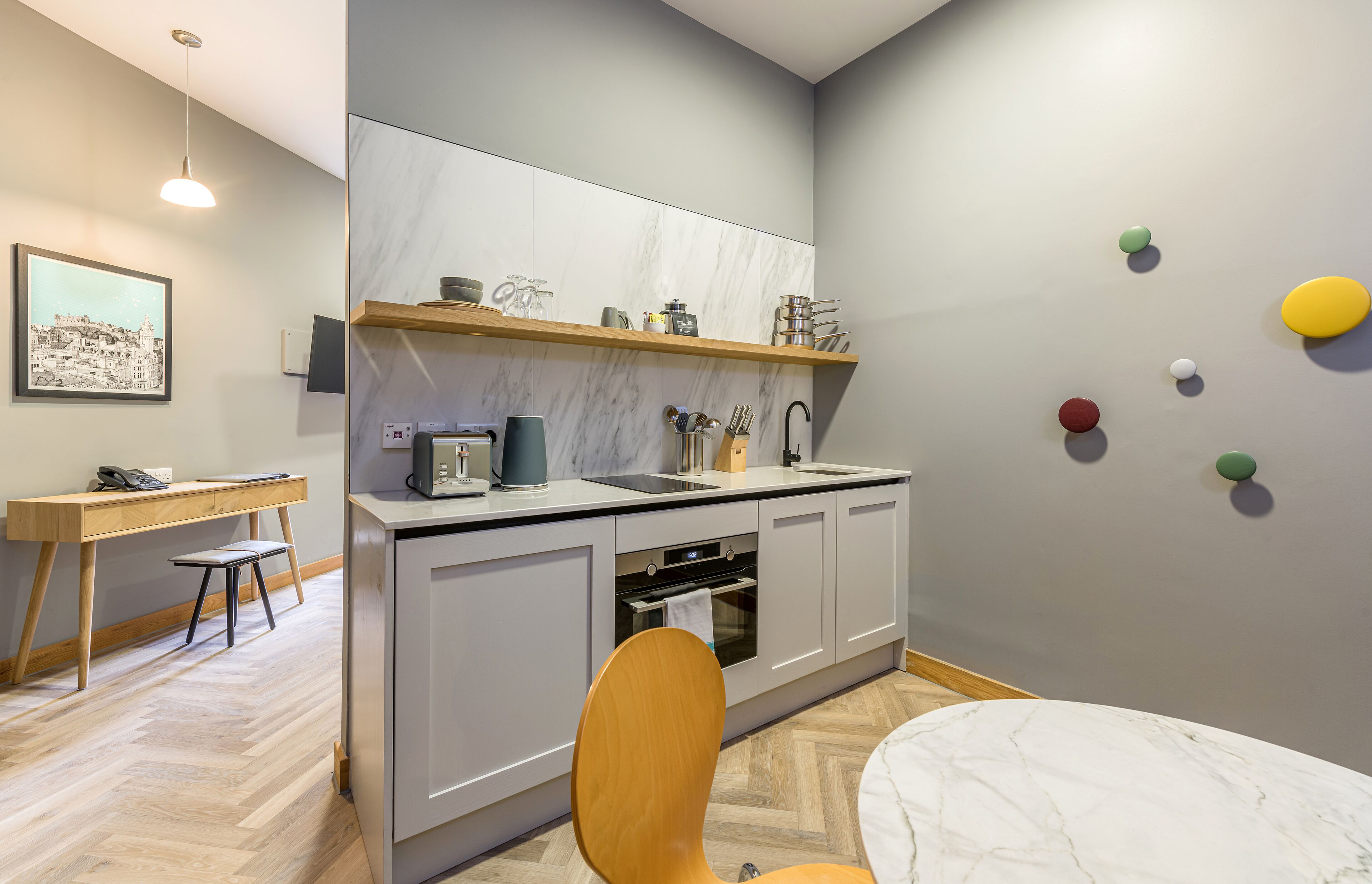 Cozinha moderna com painel de backsplash de mármore, bancada de madeira e área de refeições com cadeira e mesa.