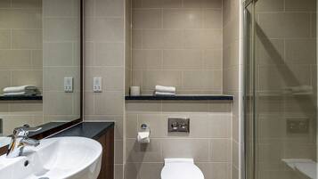 Un baño moderno con un lavamanos blanco, un inodoro y una cabina de ducha de vidrio.