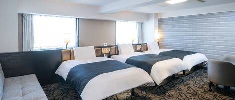 A hotel room with two beds, a sofa, a chair, and a large window with curtains.