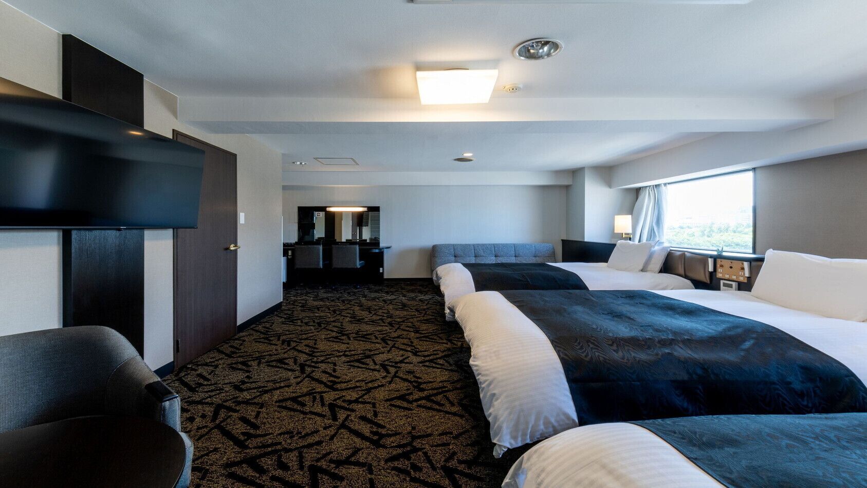 Una habitación de hotel con una cama grande, un escritorio y vistas al exterior.