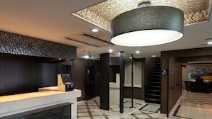 A hotel lobby with a reception desk, a digital check-in kiosk, a staircase, and a patterned floor. - APA Hotel Tokyo Ojima (Tokyo)