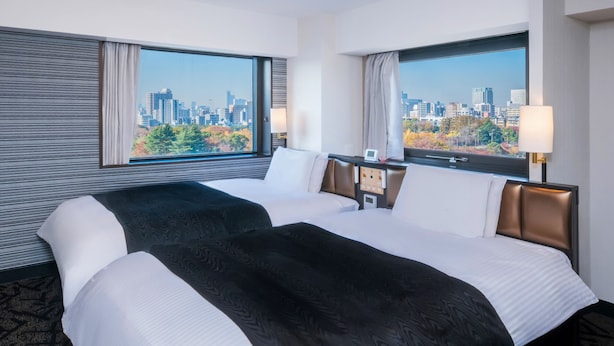 A hotel room with two beds, a city view, a control panel, and a window with curtains. - APA Hotel Tokyo Ojima (Tokyo)