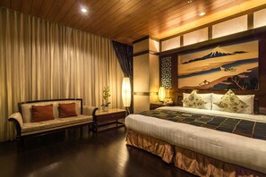 Une chambre d’hôtel avec un lit, un canapé, une table de chevet et un tableau au mur.