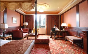 A hotel room with a large bed, a desk, a chair, and a sofa. There is a window with curtains, a lamp, and a painting on the wall. - Capital Hotel Dazhi (Taipei)