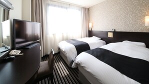 Een hotelkamer met twee bedden, een bureau met telefoon, een televisie en een kamer met een patroon.