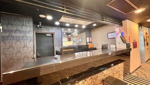 Een hotel receptie met een marmeren balie, een receptie bureau en een deur.